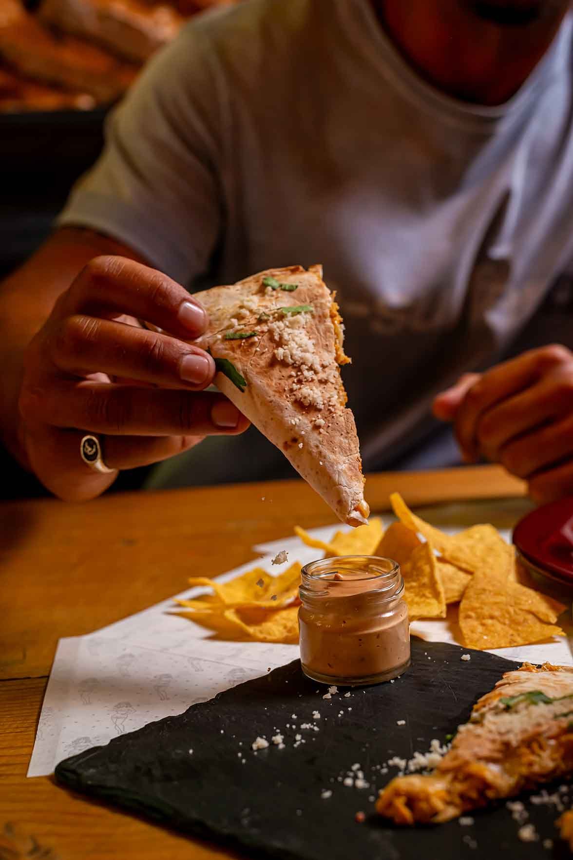 Dipping a quesadilla into a creamy sauce