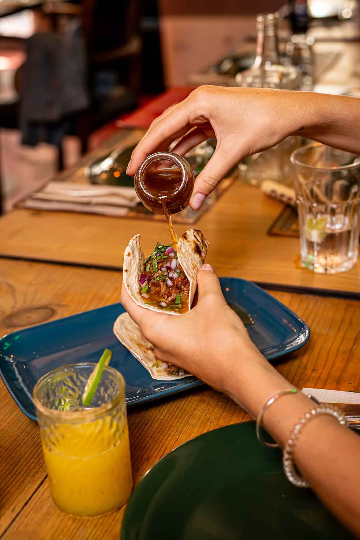 Pouring sauce over a carnitas taco